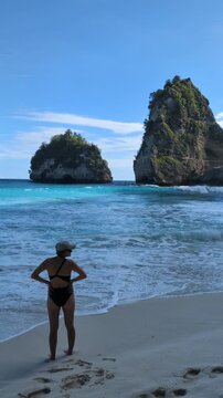 Blonde woman in bikini at Diamond Beach Bali Indonesia, tropical paradise with turquoise ocean and iconic cliffs, smiling female posing on sandy shore, travel wellness moment in exotic island seascape