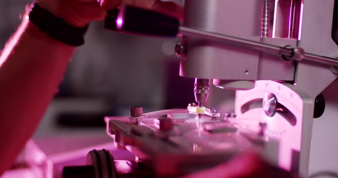 Close up of precision optical lens drilling machine in a laboratory with purple lighting