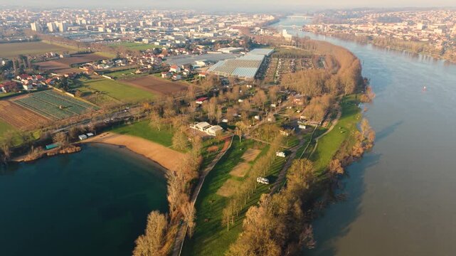 Villefranche-sur-Saone,Rhone,France highl drone footage of Aire on the banks of the River Saone and lake and beach with views over the river and town in golden misty sun
