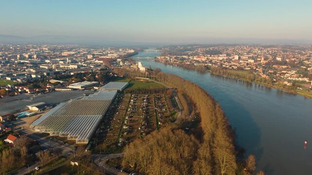 Villefranche-sur-Saone,Rhone,France reveal drone footage along the River Saone of allotments and riverside campsite with industrial estates,houses,bridges and distant views in misty golden sun