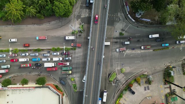 Aerial top-down view of a four-way intersection with a flyover roadway during traffic - General Luna St, Iloilo, Philippines