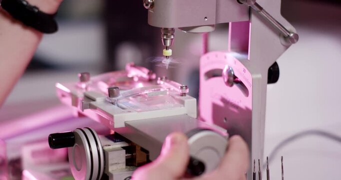 Close up of precision optical lens drilling machine in a laboratory with purple lighting
