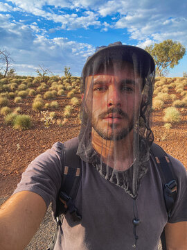 Young man exploring outback wearing insect head net