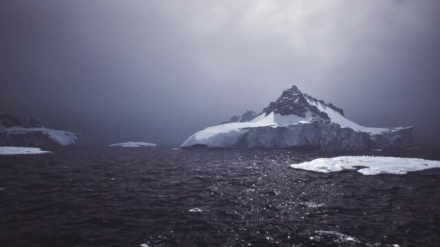 dark sea dotted with scattered floes, black water and glittering ice fragments, subdued light and heavy clouds create somber maritime mood with environmental