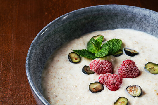 Healthy oatmeal porridge topped with frozen raspberries