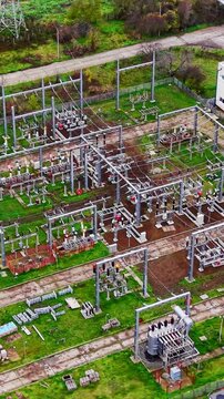 Detailed aerial view of transformers, circuit breakers, and busbars in a power distribution facility. High angle view of high voltage electrical substation. Vertical video.