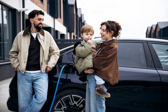 Family with child charging their electric vehicle on a residential street, promoting sustainable transportation and modern living