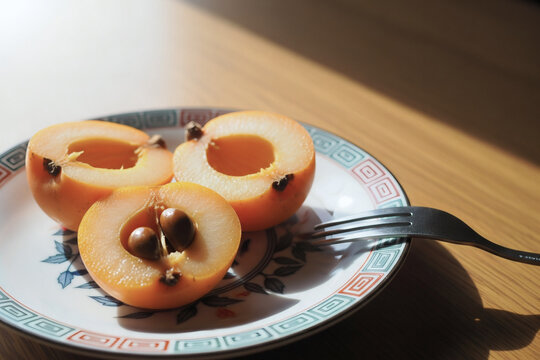 カットしたビワを皿に盛りフォークで食べる準備をした静物