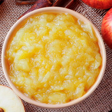 homemade apple sauce or apple puree in ceramic bowl over rustic wooden table. top view