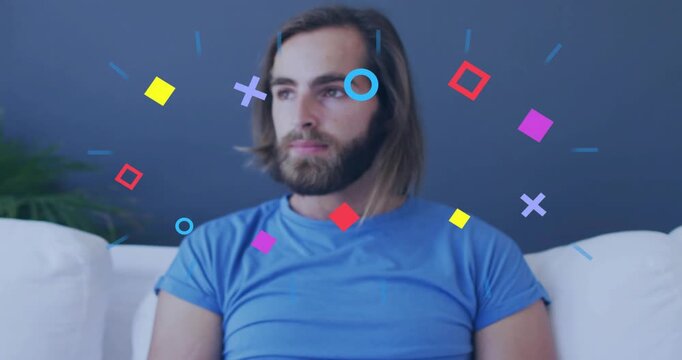Watching smartphone, adult man in blue T-shirt lifting head on white couch, shapes orbiting