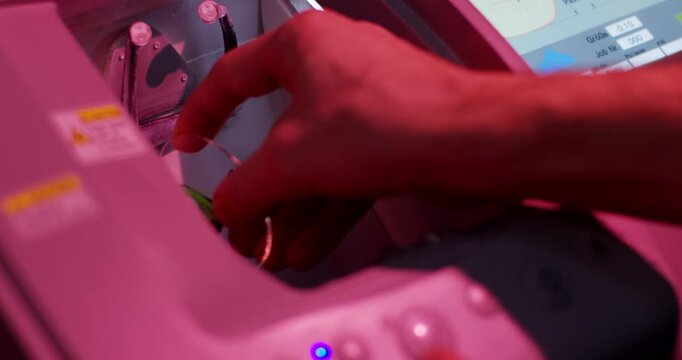 Close up of technician hands removing a finished lens from an optical edger machine in a laboratory