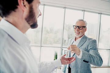 Fototapeta premium Business partners in a modern office exchange a small bottle during a friendly professional moment