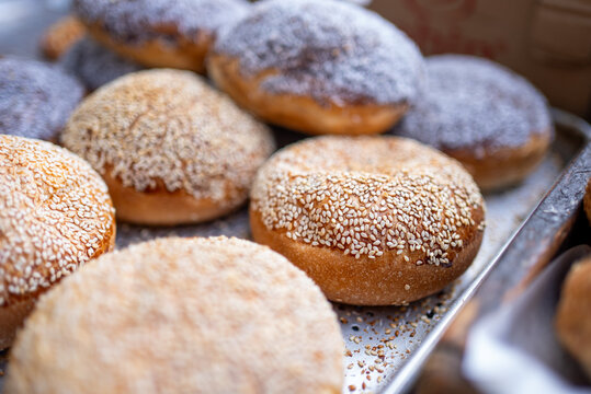 Fresh Sesame Buns and Powdered Sugar Donuts on Bakery Tray