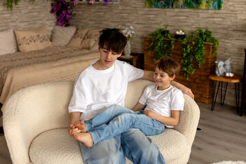 Obraz premium Happy positive children, tickling on the feet, having fun together, boy brothers at home having wonderful day with joy