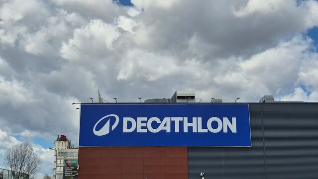 A large blue sign with the white "DECATHLON" logo and brand name mounted on a modern building under a cloudy sky. Photo taken on April 8, 2026 in Bucharest, Romania.
