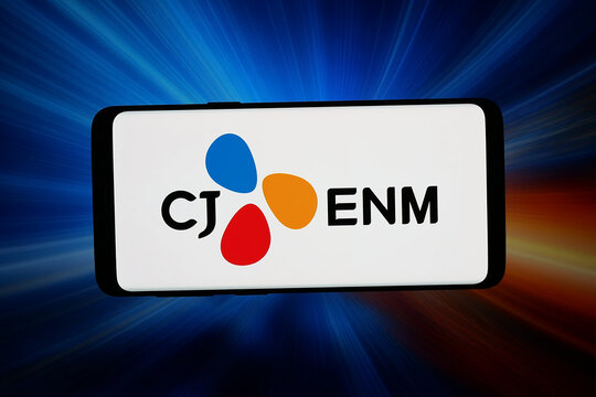 Stuttgart, Germany - 04-02-2026: In this photo illustration, the logo of Korean entertainment company CJ ENM Co. Ltd. is displayed on a smartphone in front of abstract background on computer screen.