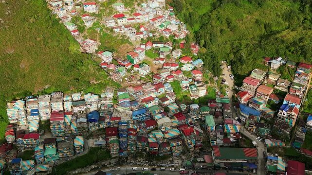Aerial overview of scenic village community with vibrant, colorful rooftops along lush hillside at Valley of Colors, Benguet, Philippines