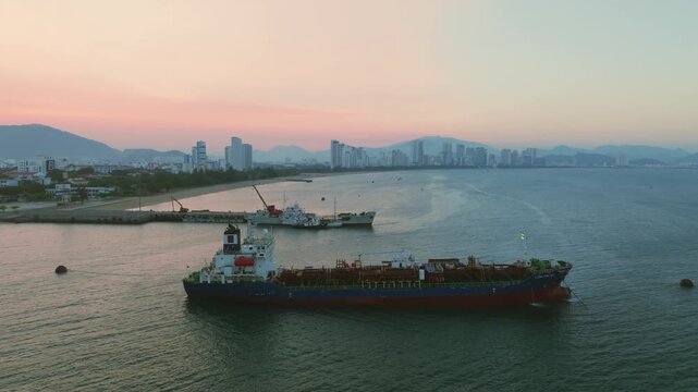 Large cargo ship and fishing fleet in Nha Trang port area aerial 4K
a large industrial cargo tanker anchored near the Lang Chut fishing village in Nha Trang, Vietnam. maritime logistics