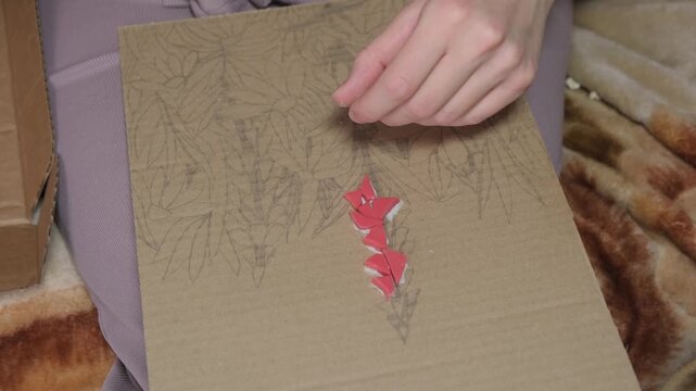 A girl creates art by laying tiles on a stenciled host
