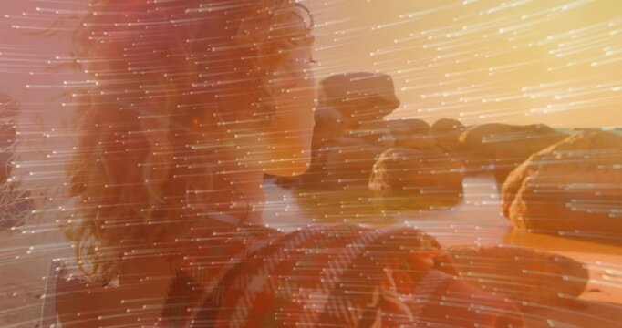 Woman shading eye from sun, turning to see sunset, reaching rocks, streak drifting for travel