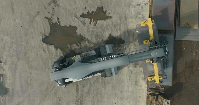 Top down aerial view of a reach stacker with magnetic lifter in an industrial metal yard