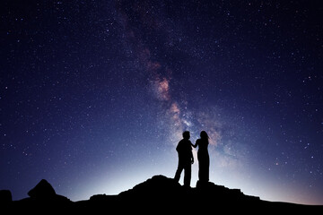 Fototapeta premium Silhouettes of lovers against the backdrop of the colorful Milky Way galaxy.