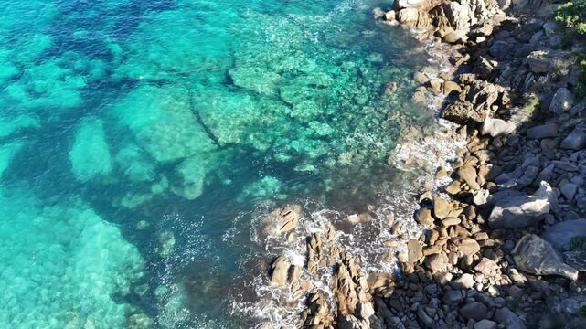 Top-Down Forward Drone Flight Over Multicolored Coastal Waters in Capo Testa, Sardegna
