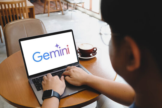 Bangkok, Thailand. April 9, 2026; An over the shoulder view of a man using a laptop displaying the Google Gemini AI logo while sitting at a cafe table.