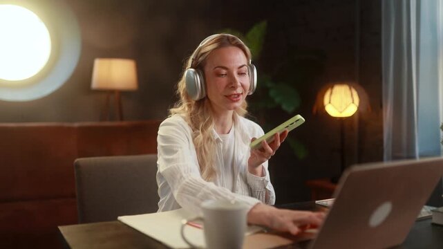 Female Preparing Notes Quickly. Energetic Woman Communicates Via Phone While Documenting On Laptop. Dynamic Female Host Engages In Voice Recording As She Types And Manages Her Workspace