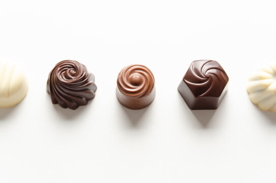 Assorted chocolate bonbons on white background. Chocolate day concept. Horizontal format with copy space. 
