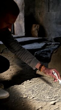 Vertical video. Male scientist historian uses soft brush to remove dust from stone slab with engraved hexagram Star of David. Historical territories of Israel. Ancient Jewish tombstone. Archaeological