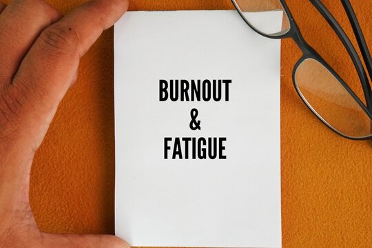 Glasses and paper with the words Burnout and Fatigue. Fatigue is temporary tiredness, while burnout is sustained, deep depletion. Synonyms for burnout include exhaustion, cynicism, and depletion.