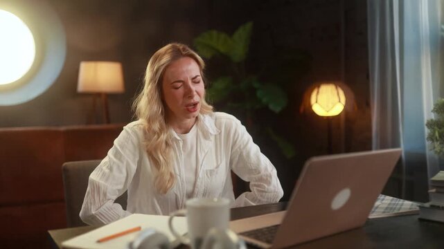 Sad unhealthy young woman clasping belly and suffering from severe abdominal pain periods spasm irritable bowel syndrome of diet while working on laptop at home
