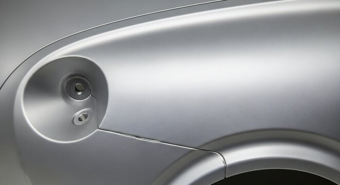 Closeup of a silver car headlight and body panel automotive design detail.