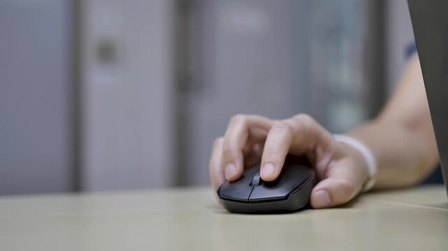 Close-up of a hand using a computer mouse on a desk. Suitable for technology, work, and everyday office activity themes.