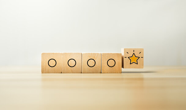Outstanding performance concept with glowing star icon on wooden blocks among simple circle symbols, representing excellence recognition, top quality rating, and standout business achievement