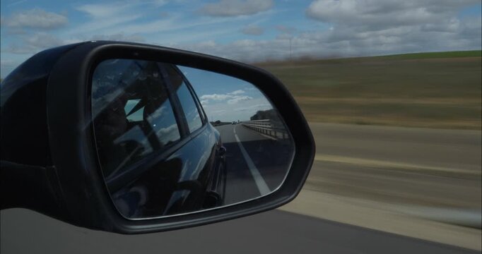 Rearview mirror POV from inside a car down the road