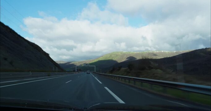 Young woman driving down an empty road in Spain in a cloudy day