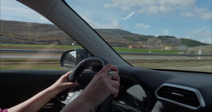 Young woman driving a car down the roads of Castilla La Mancha in Spain
