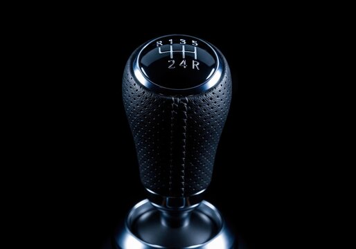 Manual car gear shift knob with black leather and silver accents isolated on dark background