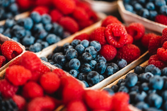 Vibrant macro shot of fresh organic raspberries and blueberries in punnets perfect for healthy lifestyle advertising summer marketing or grocery design