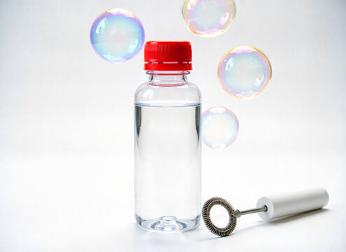 plastic bottle of bubble solution anda round bubble wand on white