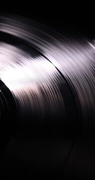 Vertical macro view of a black vinyl record spinning with luxury cinematic lighting and contemporary analog music aesthetic.