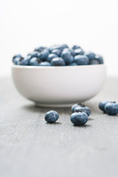 bilberry fruits at china bowl, on dark wood table