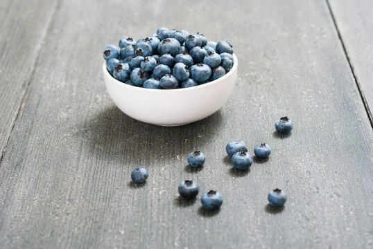 bilberry fruits at china bowl, on dark wood table
