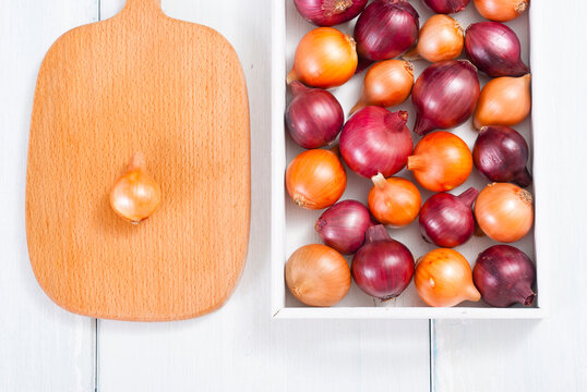 onions on white wood tray, wooden table background