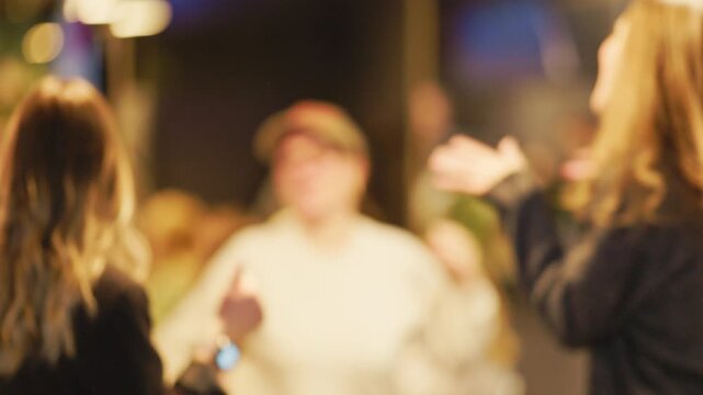 Blurry background: Informal cafe setting with people talking and screens glowing