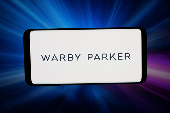 Stuttgart, Germany - 04-02-2026: In this photo illustration, the logo of US eyewear retail company Warby Parker Inc. is displayed on a smartphone in front of abstract background on computer screen.