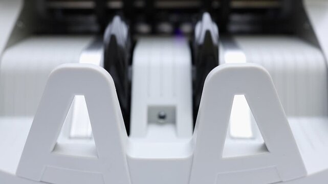 Macro shot of banknote counting machine with Vietnamese Dong money (VND). Automatic currency counter equipment processing paper bill with Ho Chi Minh portrait vignette. Finance industry in Vietnam.