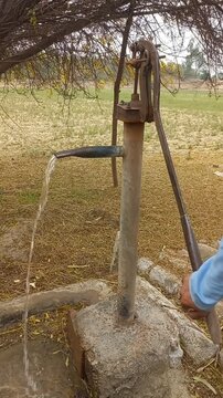 Water Flowing from Hand Pump in Rural Area of Pakistan. Clean Water from Manual Hand Pump in Village Environment. Groundwater Pump Providing Fresh Drinking Water &ndash; Rural Life Scene.